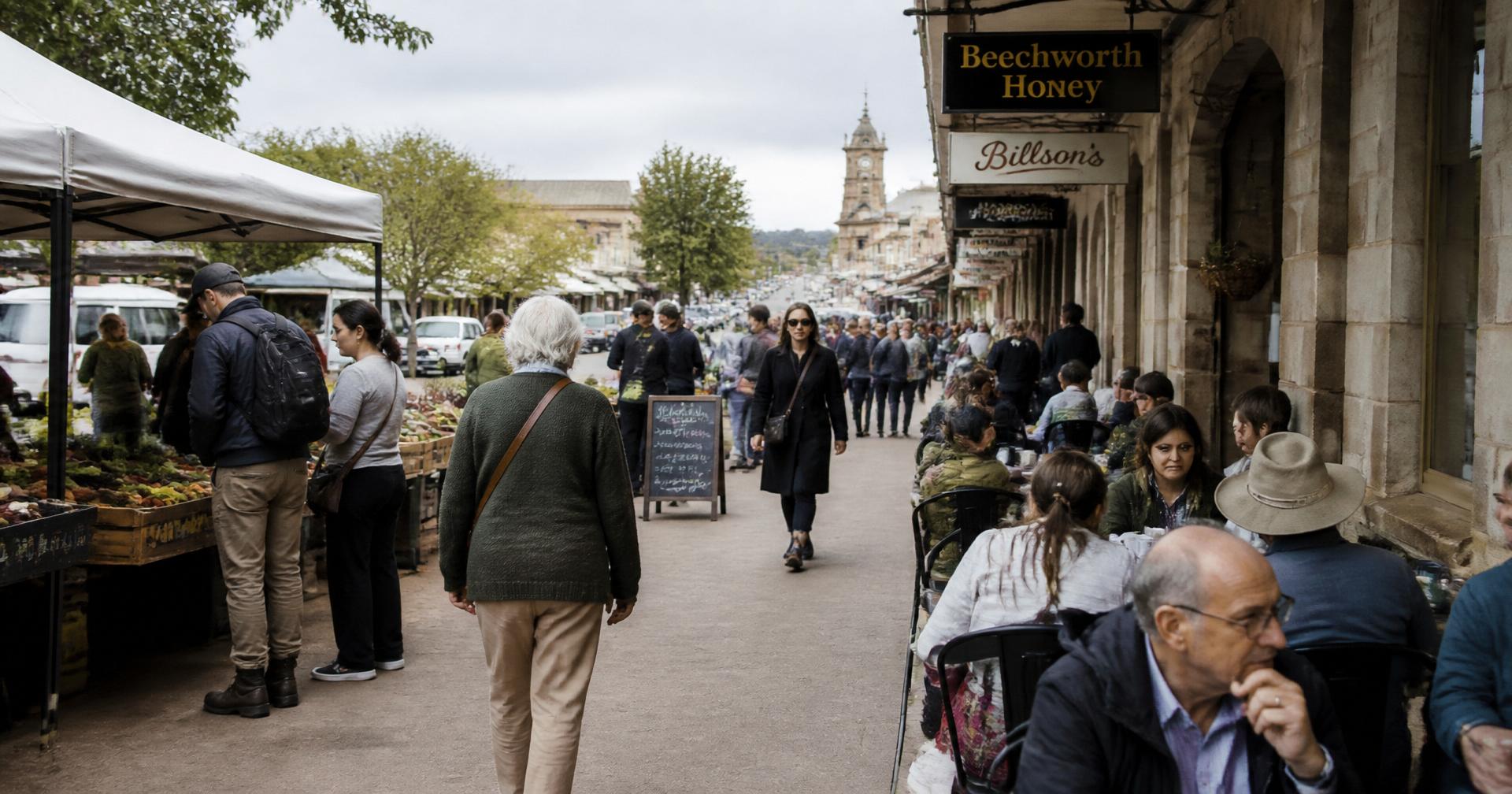 A regional Australian main street on market day, visitors browsing stalls and cafés