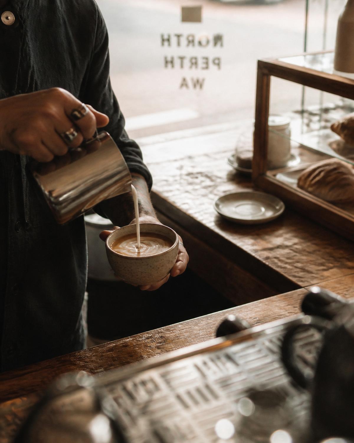 Barista pouring a warm coffee in a small independent café